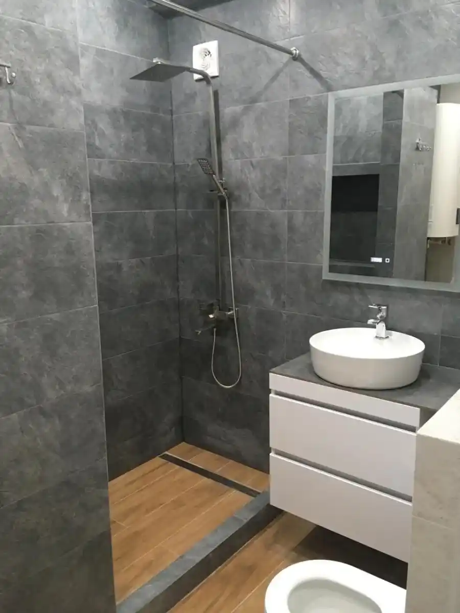 Ванная комната со строительным душевым поддоном. Цвета плитки - дерево и бетон